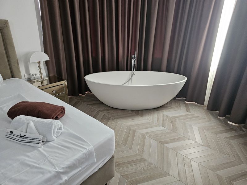 Luksuzna spavaća soba sa samostojećom kadom i chevron podnim pločicama - postavljanje pločica