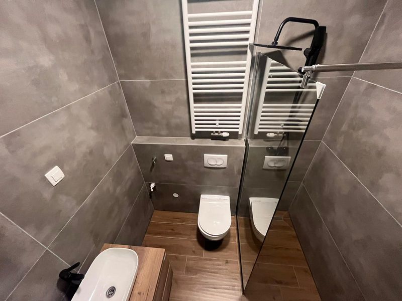 Renovirana kupaonica sa sivim velikoformatnim pločicama, tušem i grijačem - adaptacija kupaonice Zagreb